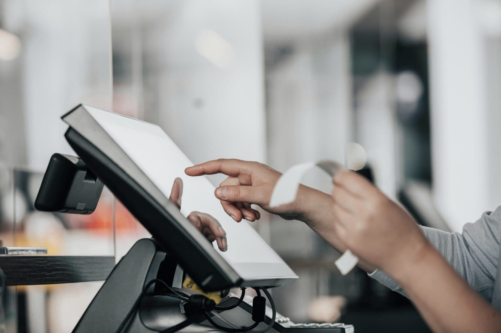 Iemand bedient een touchscreen aan een balie